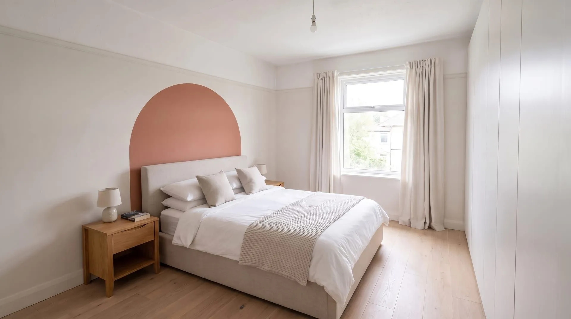 A bedroom with a terracotta painted arch behind the headboard