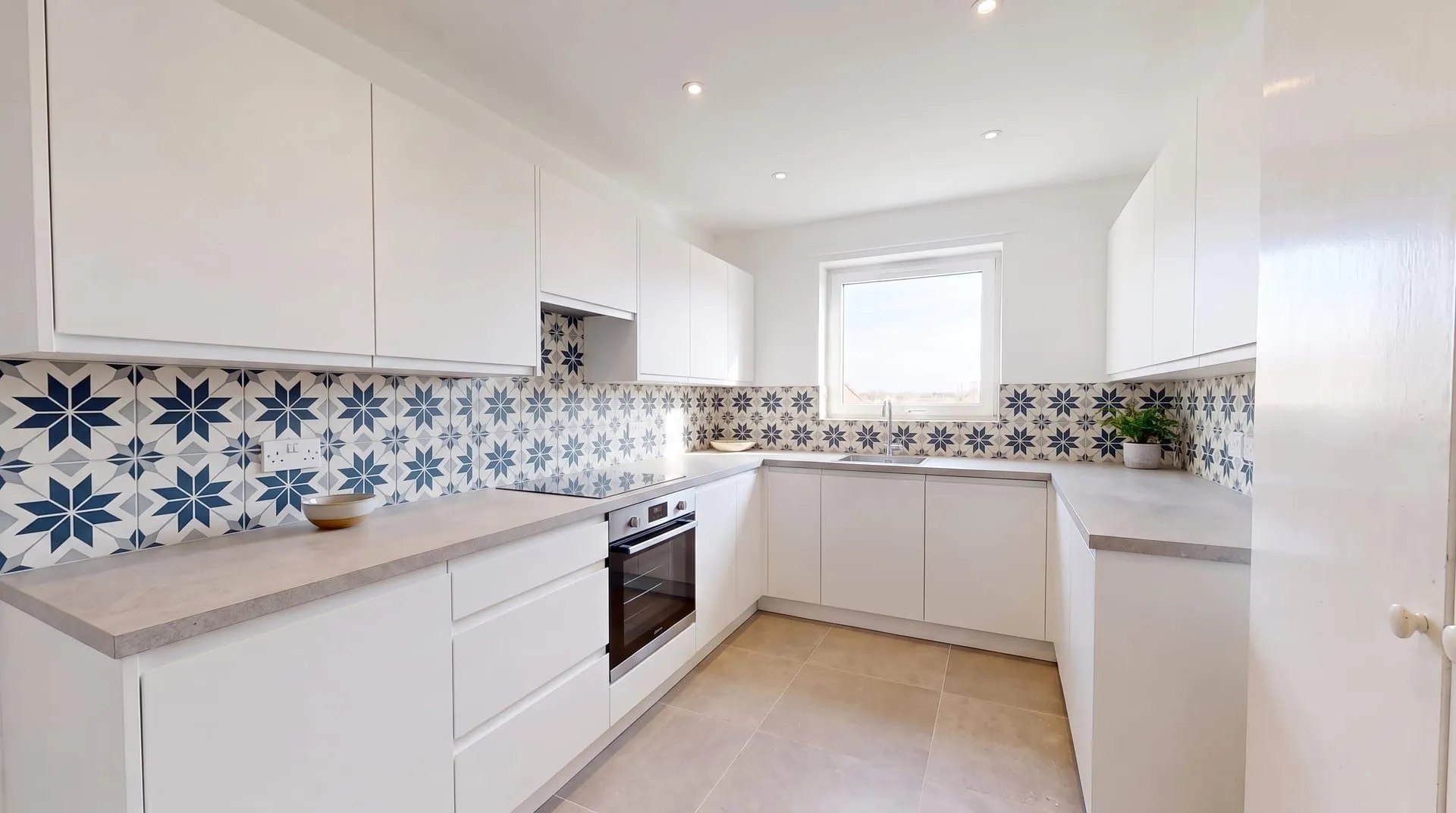 The same kitchen with a navy blue, white and grey patterned star tile backsplash