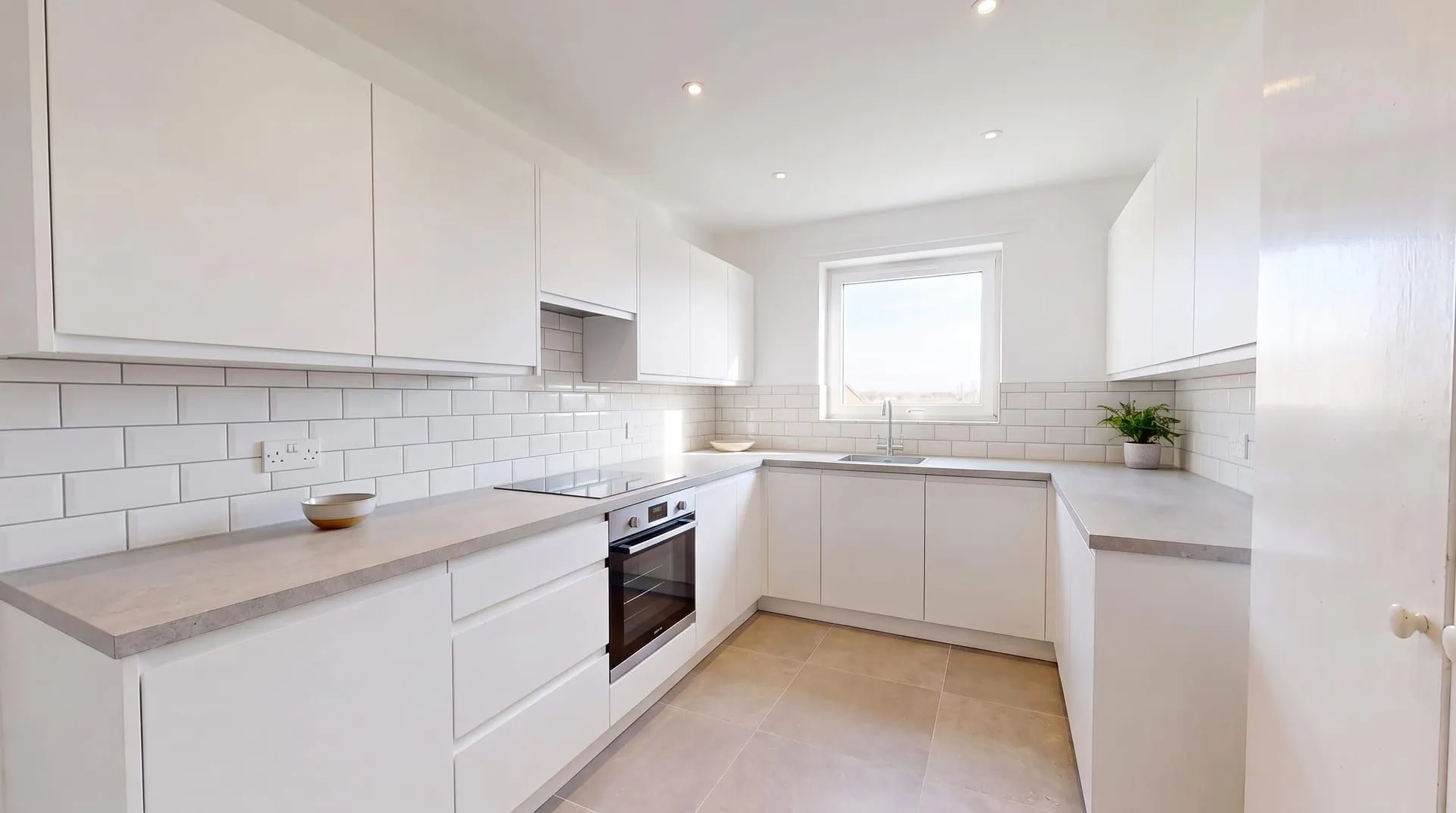 The same kitchen with a white glossy subway tile backsplash laid in a running bond with light grey grout