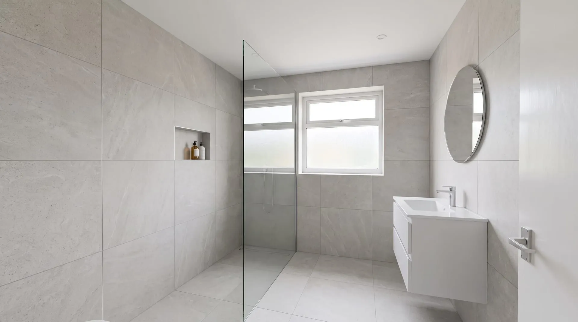 A small bathroom redesigned in a minimalist style with a walk-in shower, a niche and a wall-hung vanity