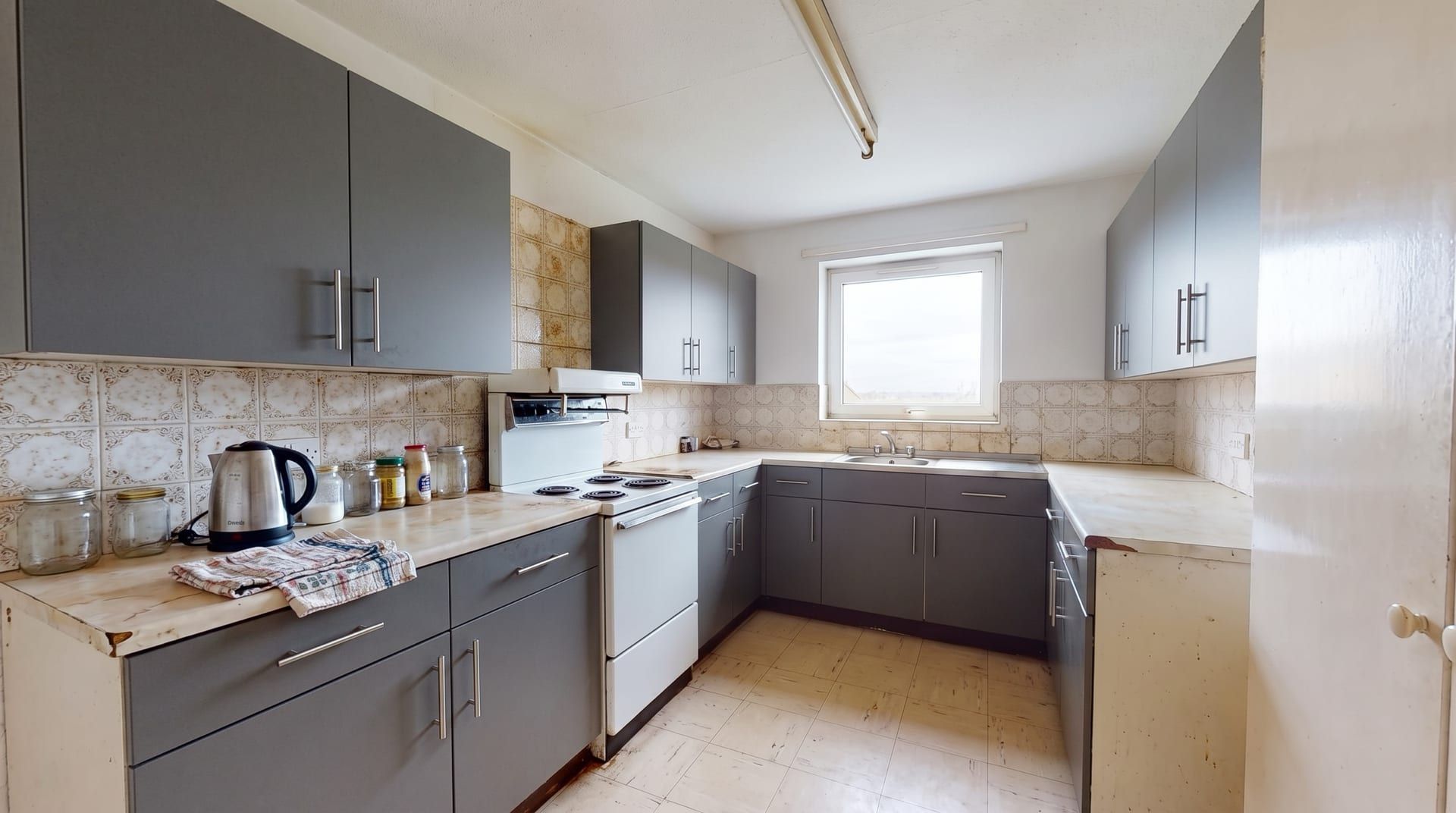 The sample kitchen with charcoal grey flat cabinet fronts and steel bar handles, everything else unchanged