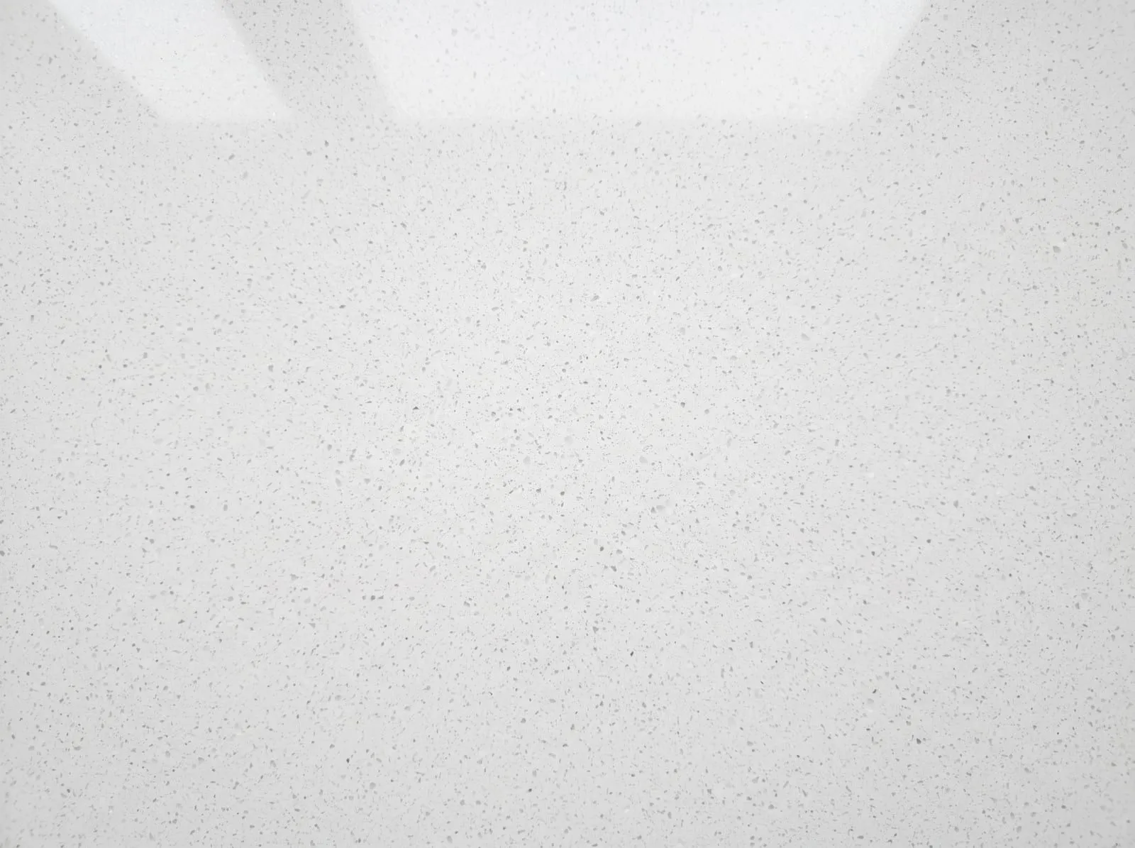 A close-up of white engineered quartz showing a uniform pattern of fine grey speckles