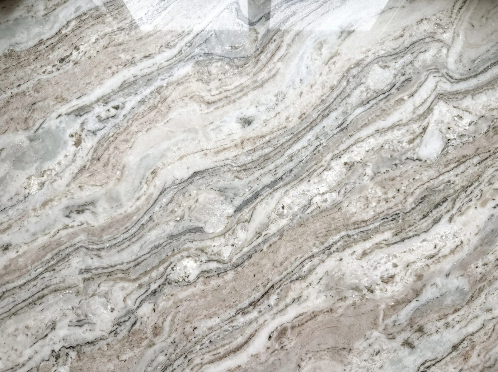 A close-up of polished quartzite with long flowing grey and beige veins and a glassy crystalline depth
