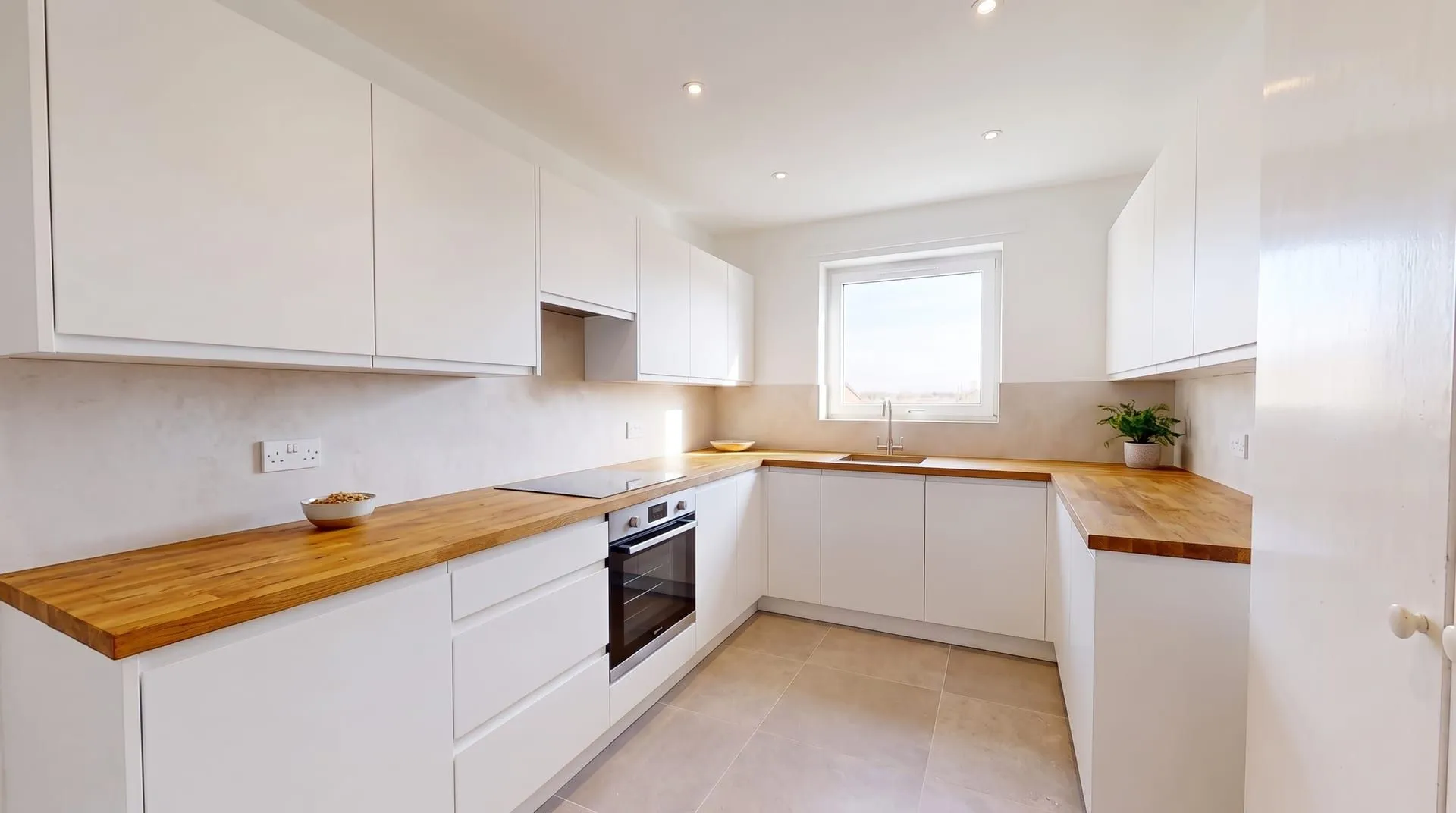 A white handleless kitchen with oiled oak butcher block countertops