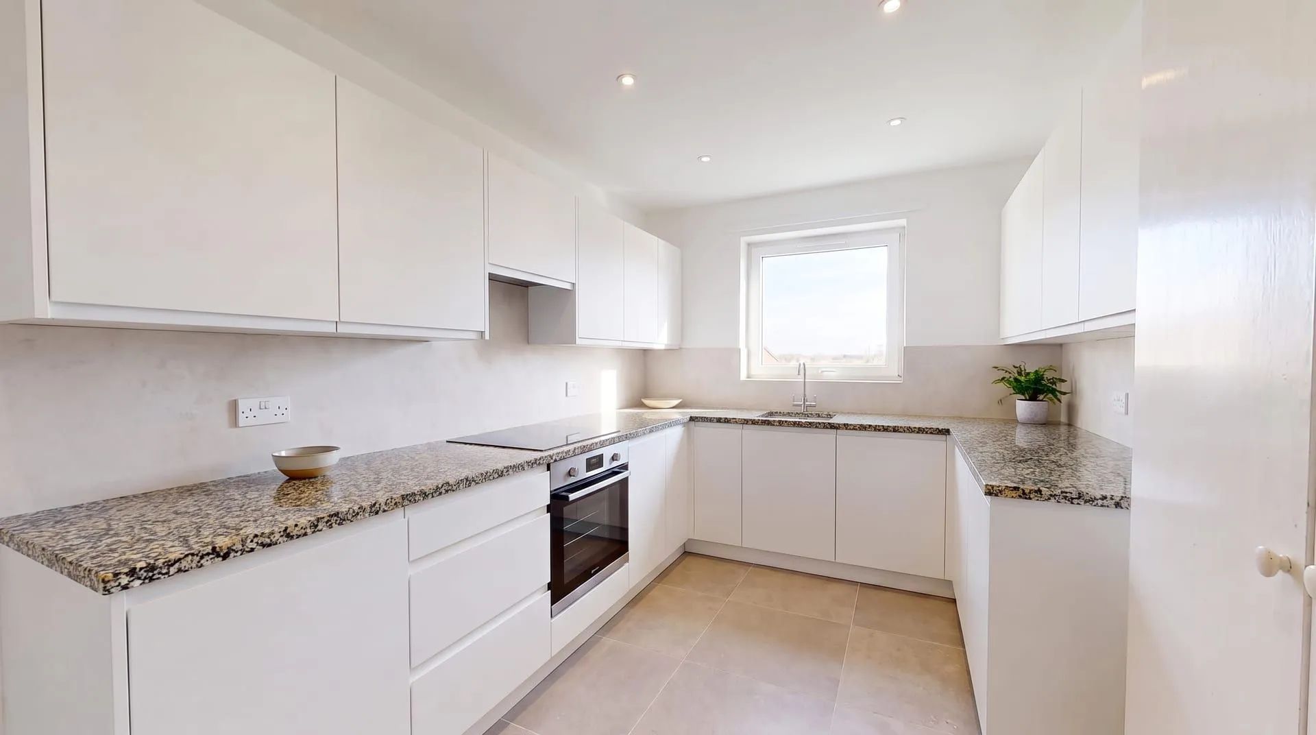 The same kitchen with a polished speckled granite countertop in black, grey, white and amber