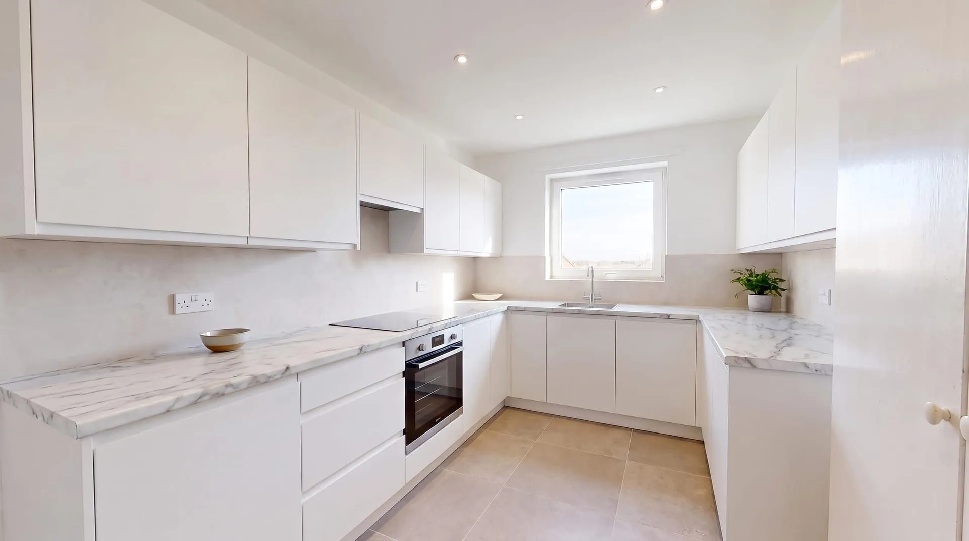 The same white kitchen with white marble print laminate countertops and a rounded front edge
