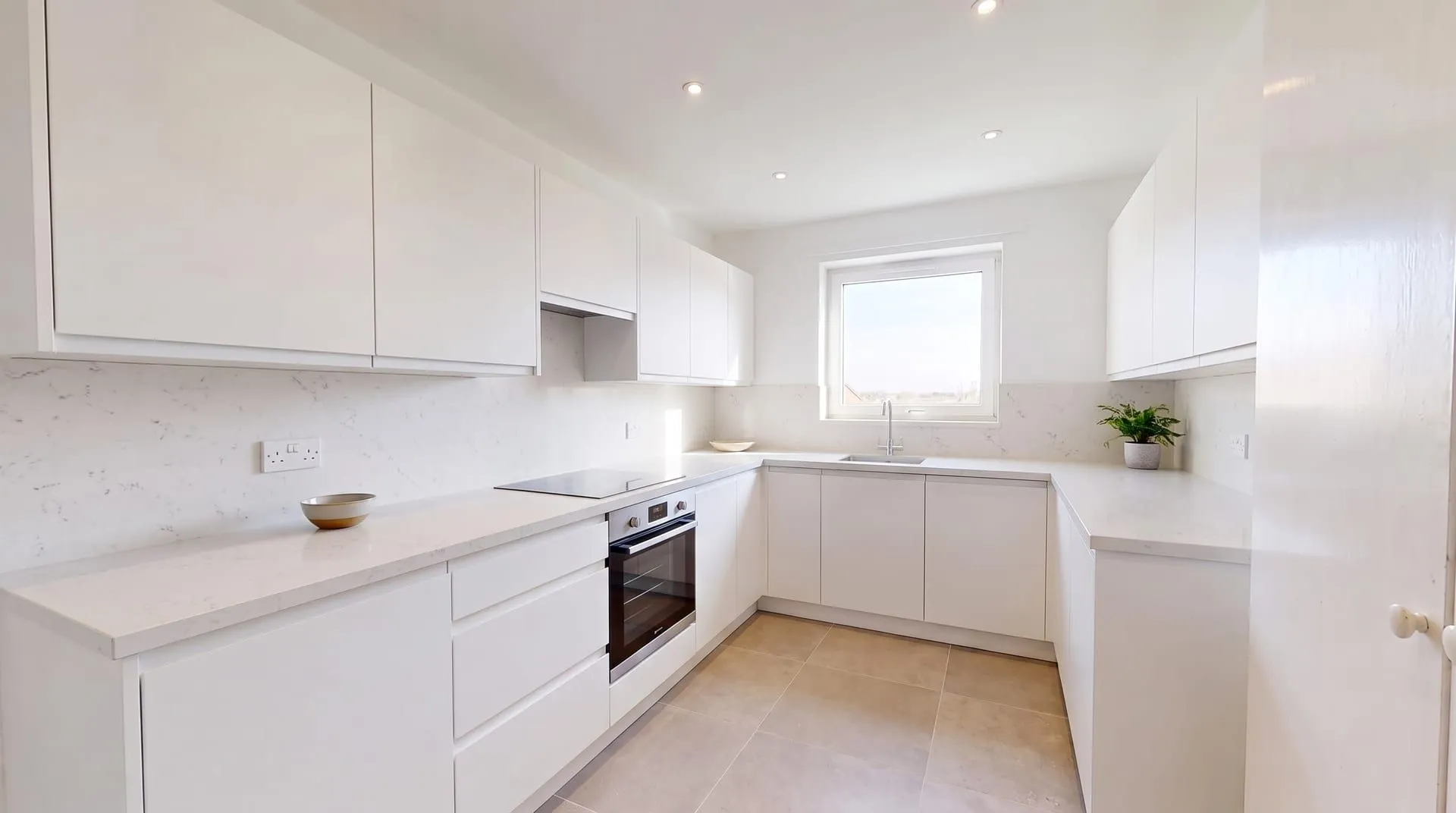 The same white kitchen with white quartz countertops and a matching quartz splashback