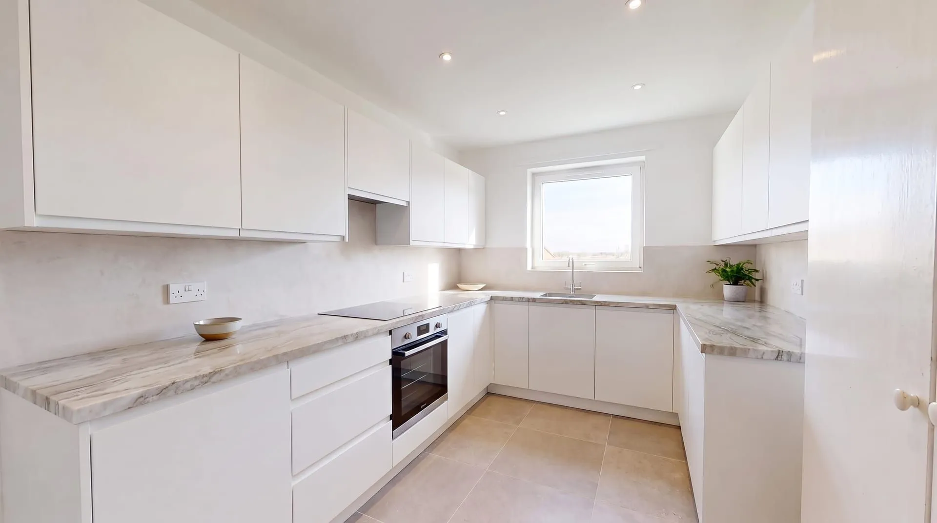 The same kitchen with a white and taupe quartzite countertop with long flowing grey veins