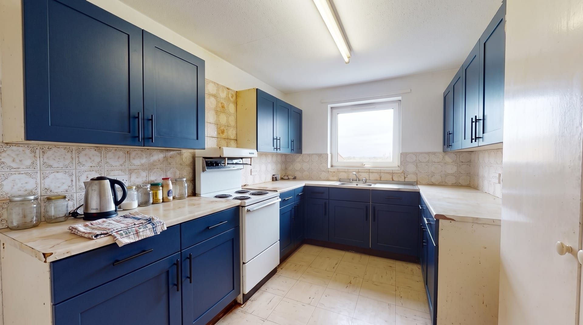 The sample kitchen with navy blue shaker cabinet fronts and black handles, everything else unchanged