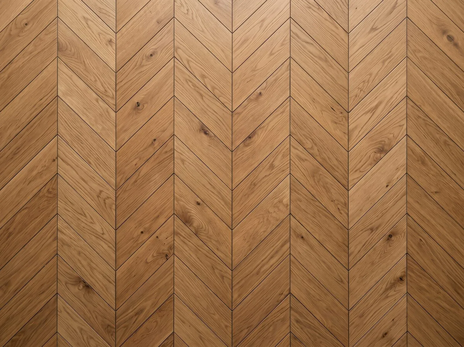 A top-down view of an oak chevron floor: blocks with angled ends meeting in a straight seam to form continuous V shapes