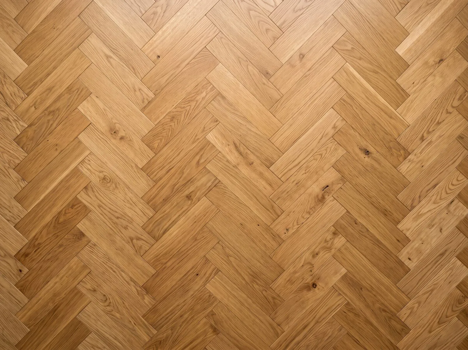 A top-down view of an oak herringbone floor: rectangular blocks with square ends in a staggered zigzag