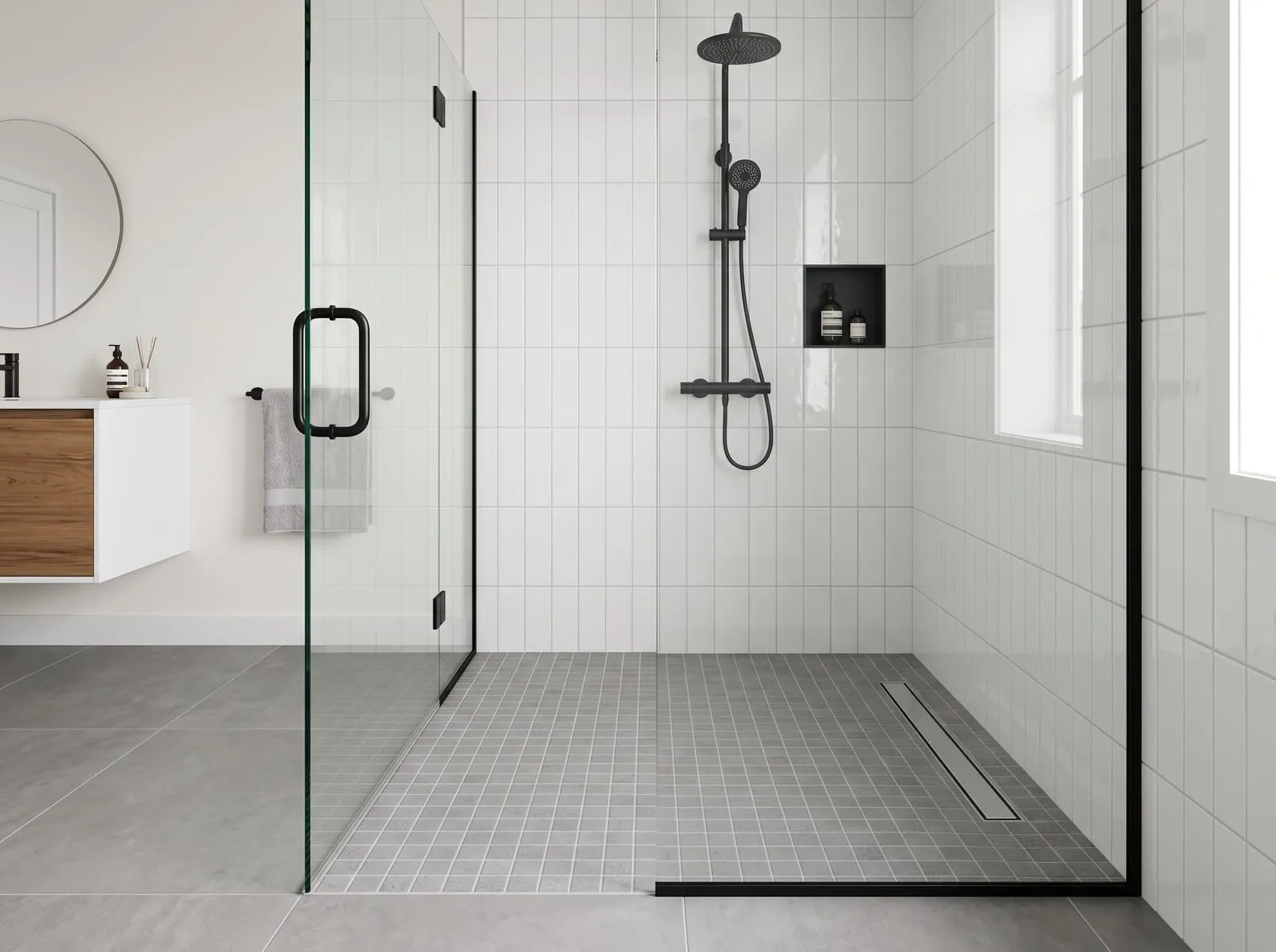 A walk-in shower with small grey porcelain mosaic tiles on the shower floor, large grey porcelain tiles on the bathroom floor and glossy white ceramic tiles on the shower walls