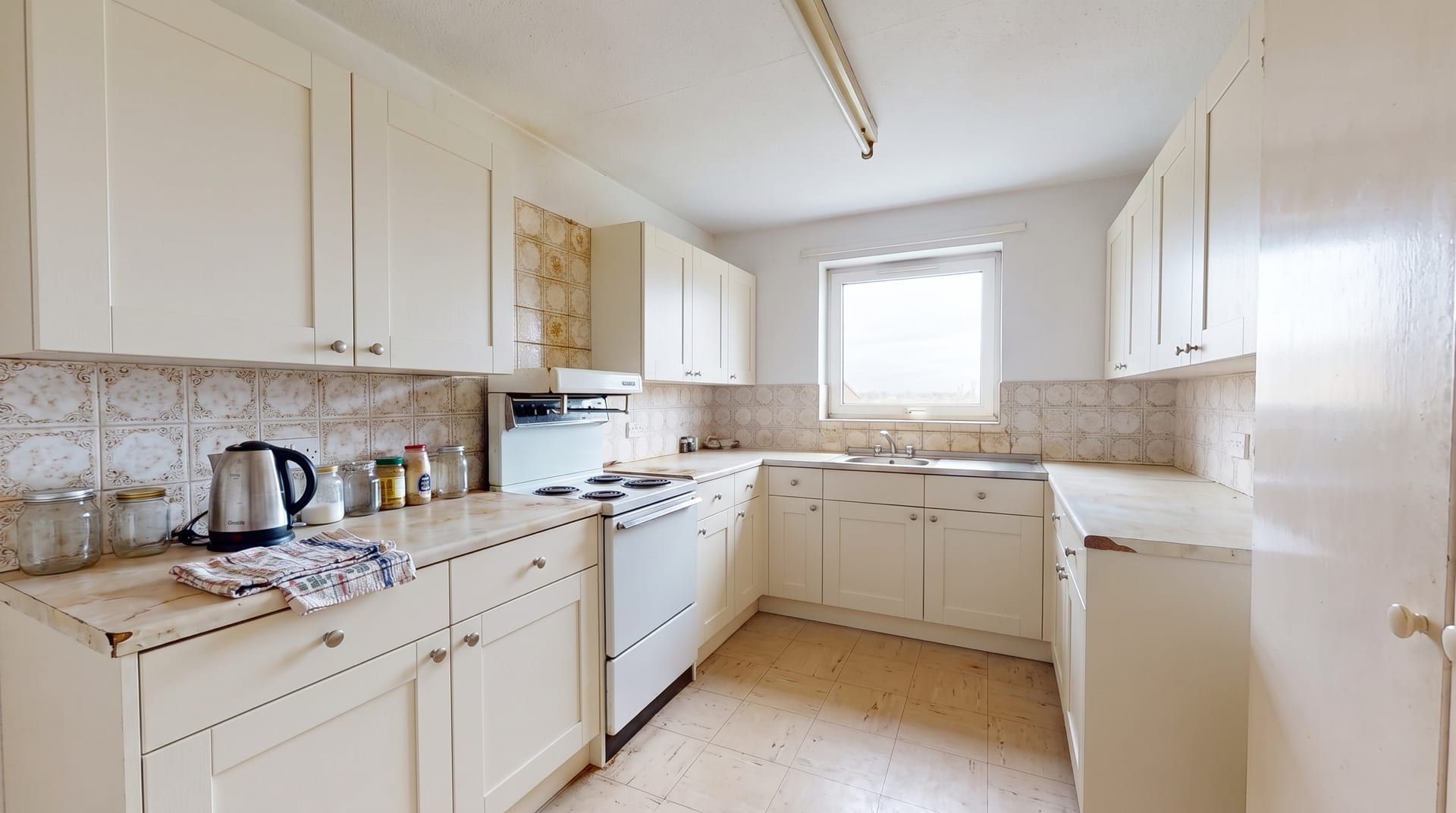 The sample kitchen with warm white shaker cabinet fronts and small round knobs, everything else unchanged